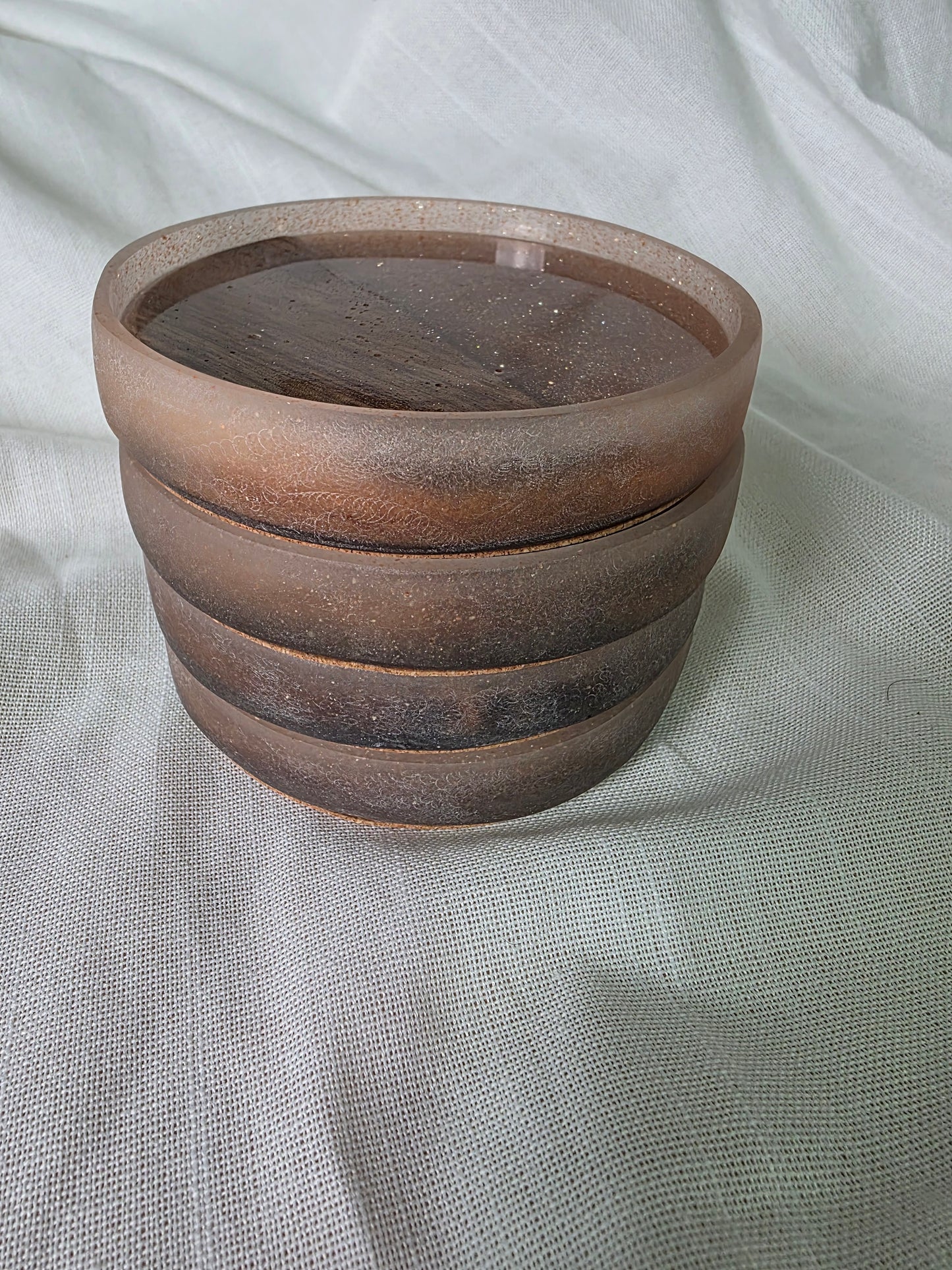 Stacking resin and wood coasters on a light fabric background