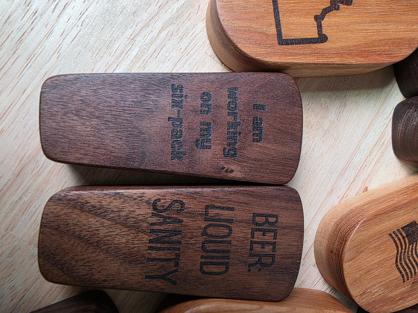 Wooden coasters with humorous text designs on a light wooden surface