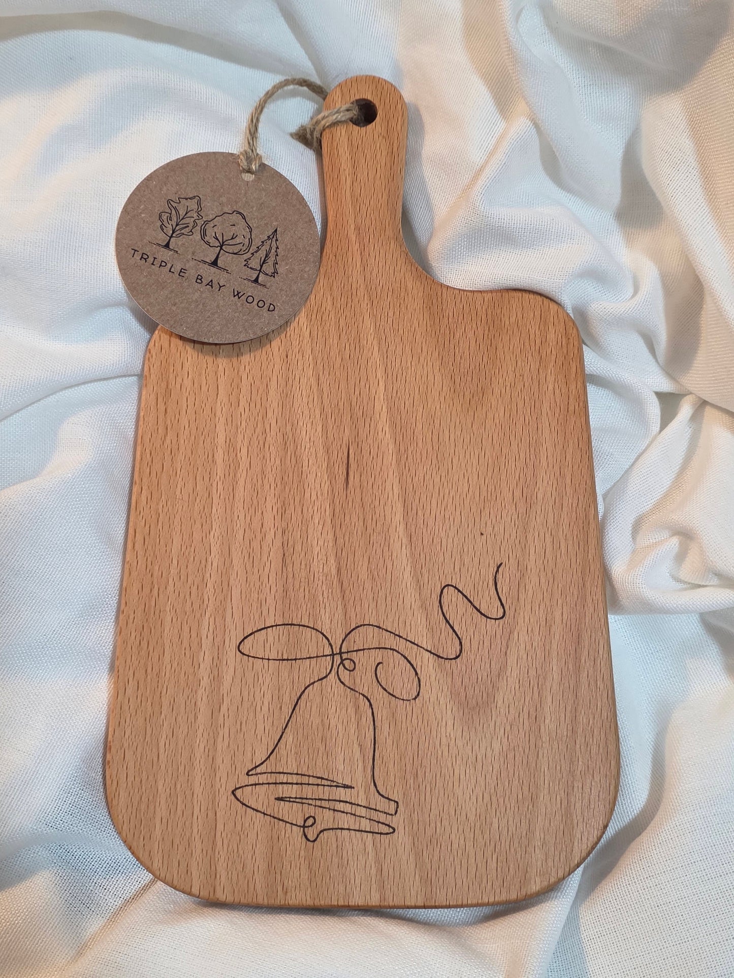Wooden paddle with engraved design and tag on a light fabric background