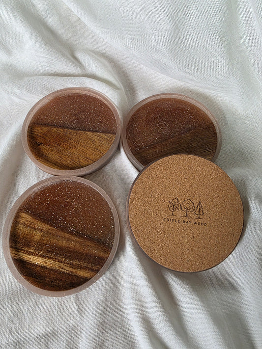 Four round wooden coasters with cork backing on a white fabric background