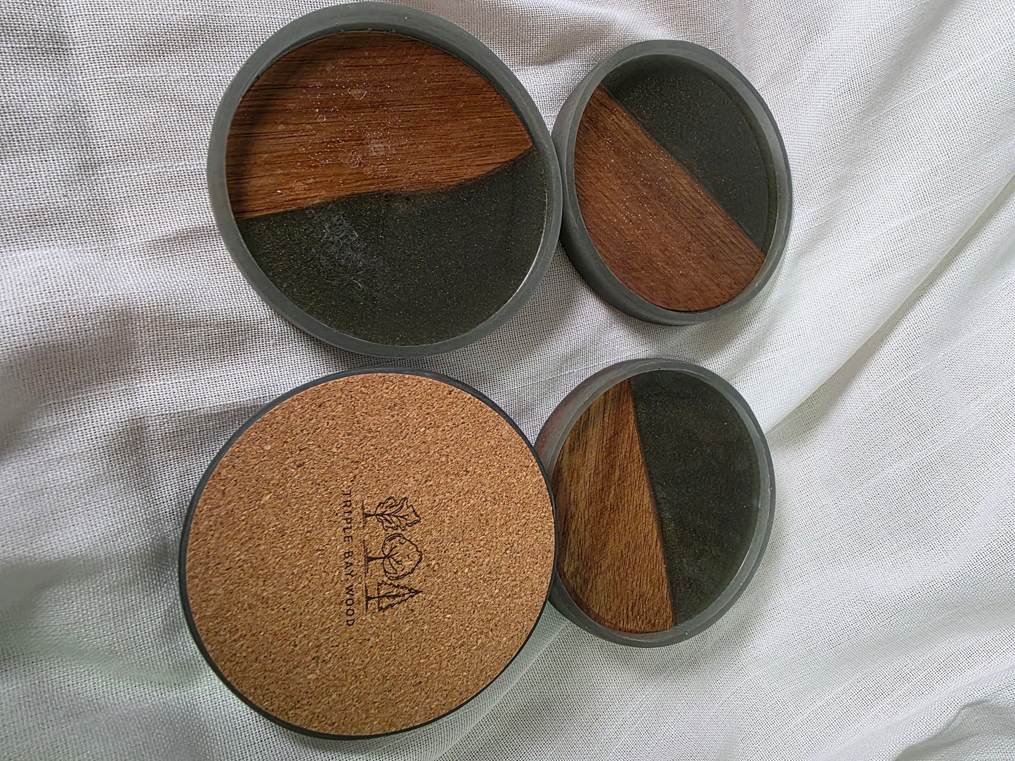 Set of four round coasters with cork and wood design on a white fabric background