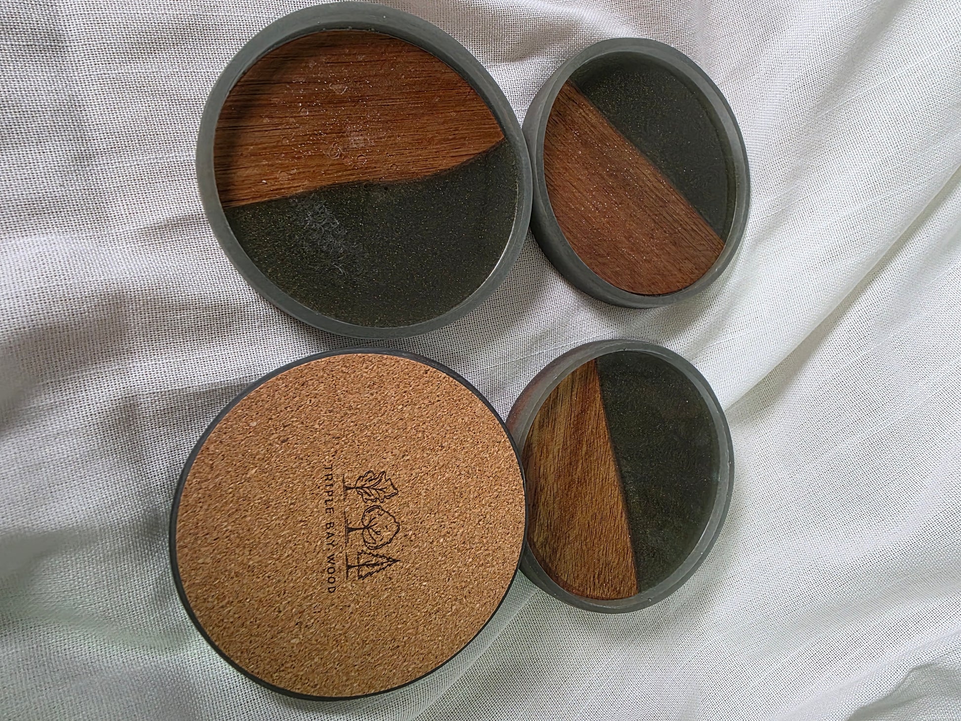 Set of four round coasters with cork and wood design on a white fabric background