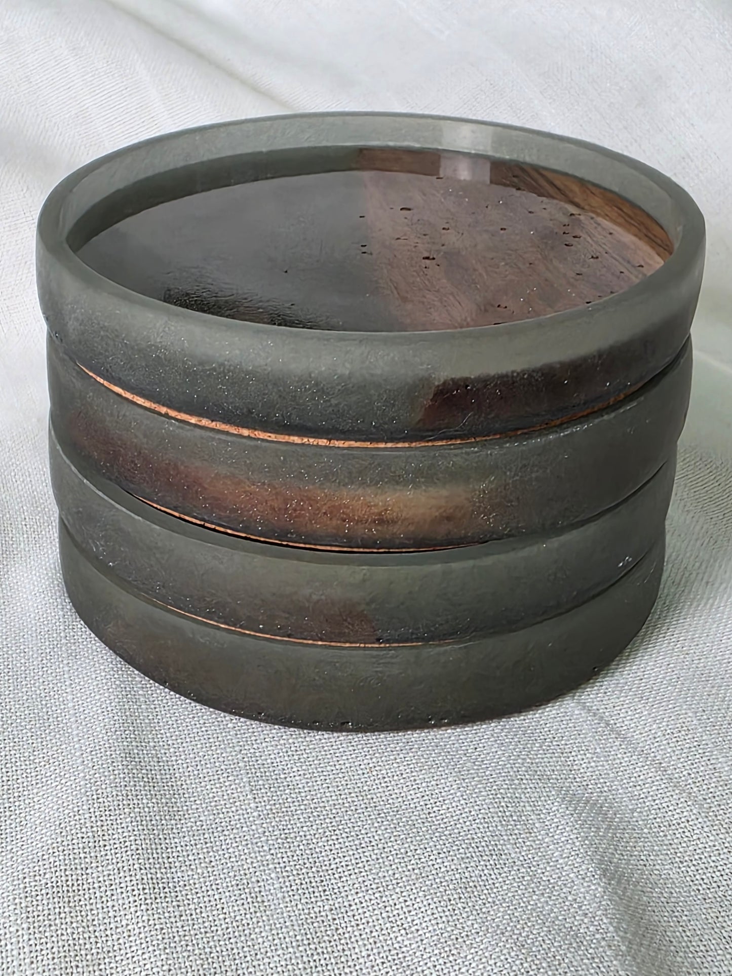 Stacking resin and wood coasters on a light fabric background