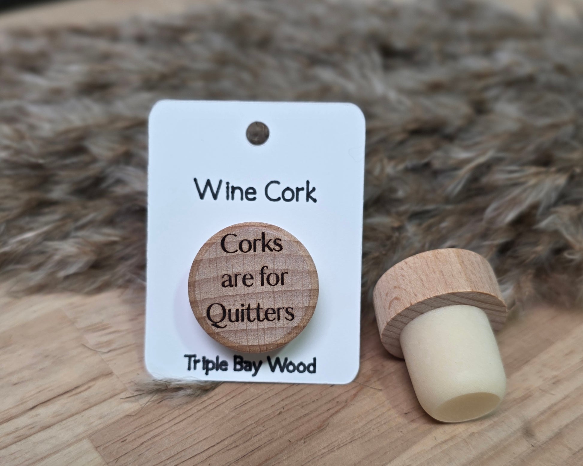 Wine cork with a humorous message on a white card, set against a textured brown background.