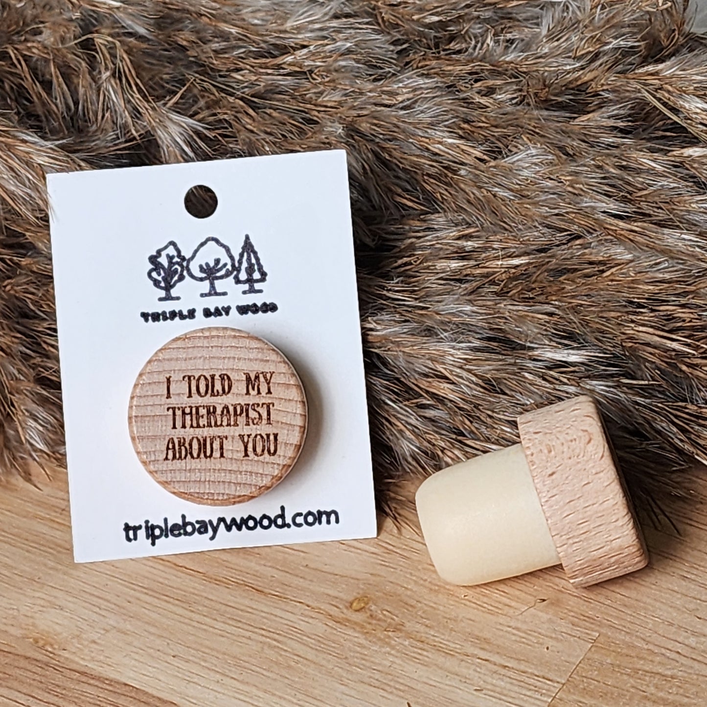 A wooden wine stopper with a humorous phrase printed on it, displayed next to its packaging which reads 'I Told MY Therapist About You'.