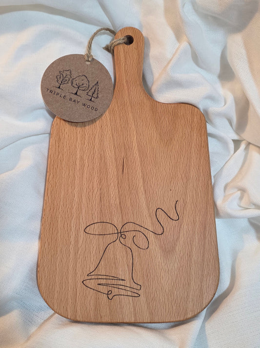 Wooden paddle with engraved design and tag on a light fabric background