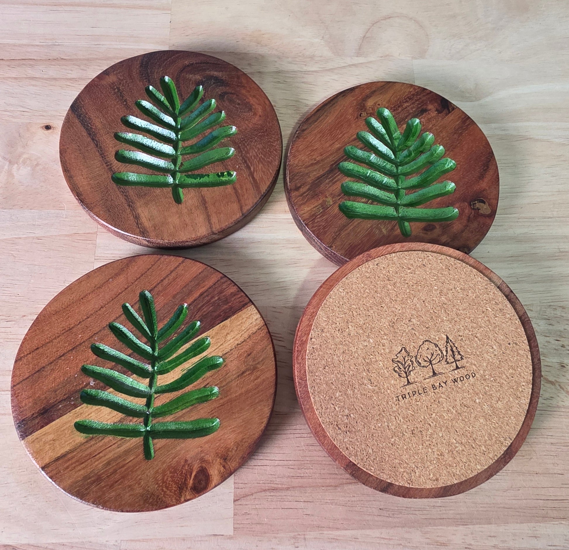 Set of wooden coasters with leaf design on a wooden surface