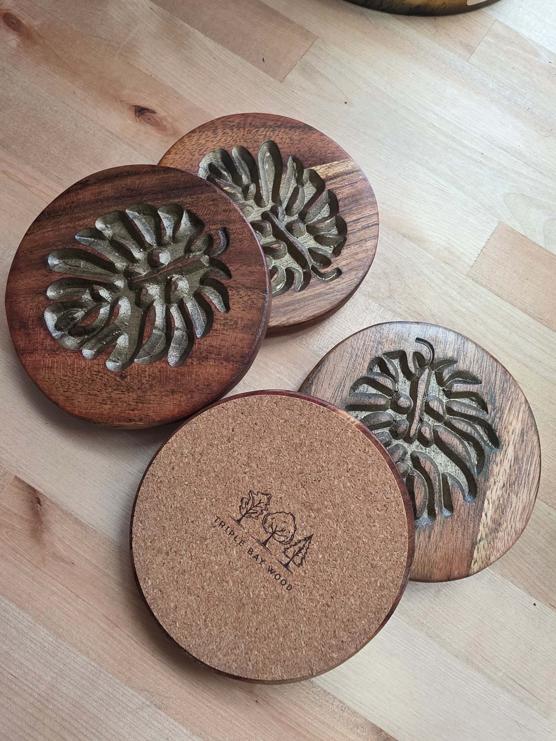 Wooden coasters with embossed designs on a wooden surface