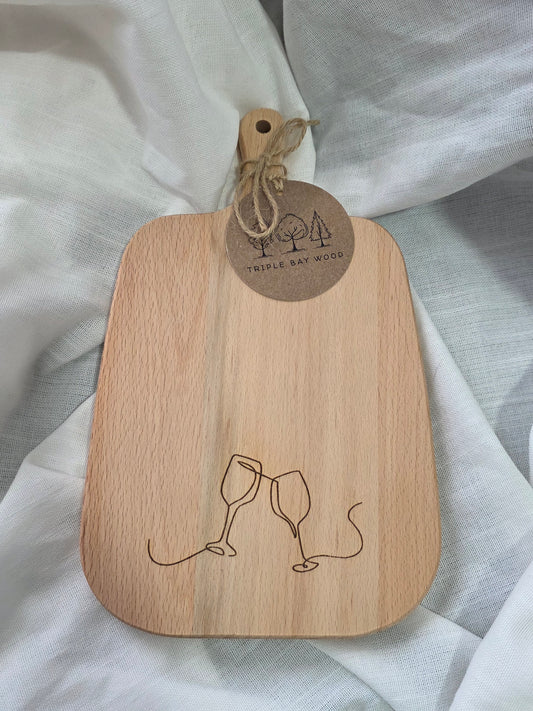 Wooden cutting board with engraved design and tag on a white fabric background