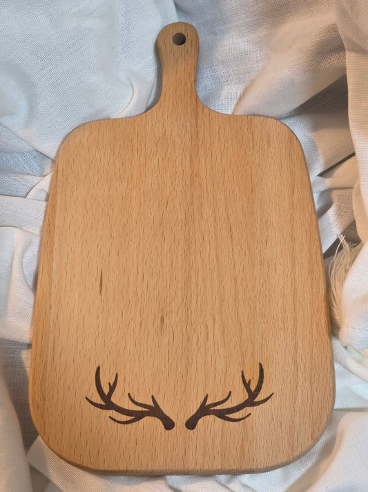 Wooden cutting board with antler design on a light fabric background